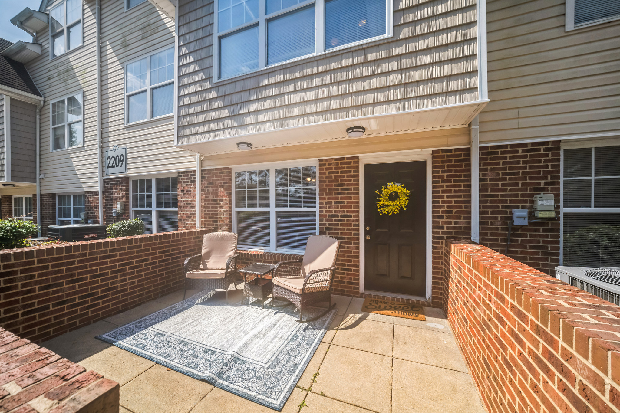 a patio with chairs and a rug on the front of a brick building